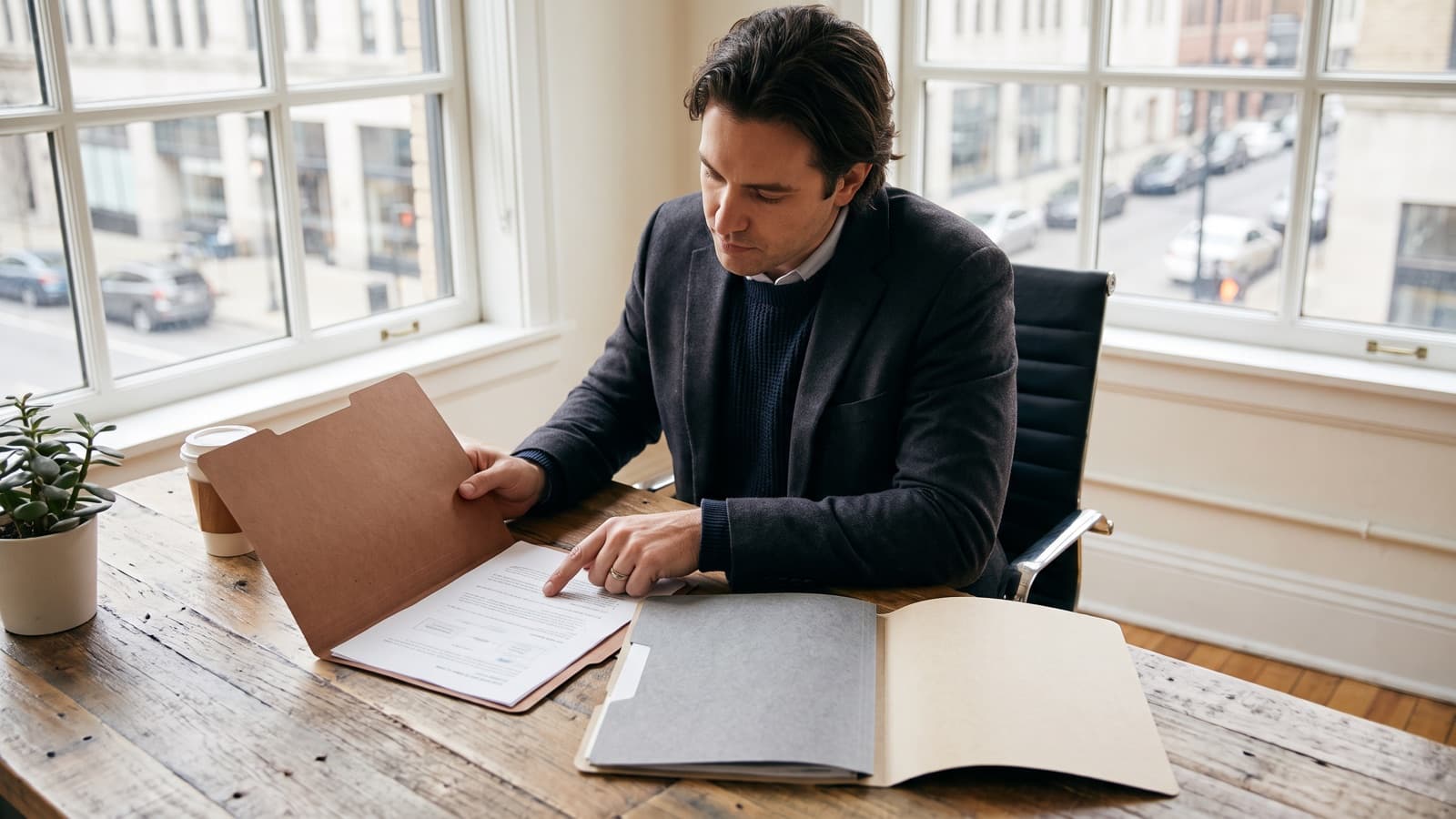 Founder at a desk comparing three folders of business registration documents