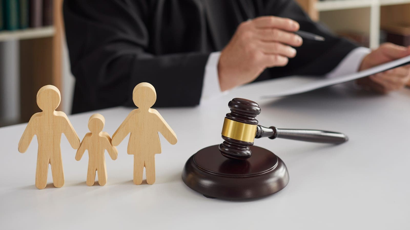 Three wooden figures of a family beside a judge's gavel on a courtroom desk