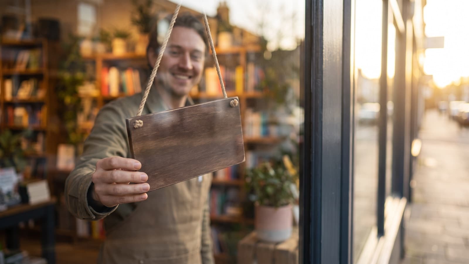 New business owner turning over an open sign on the glass door of a small shop