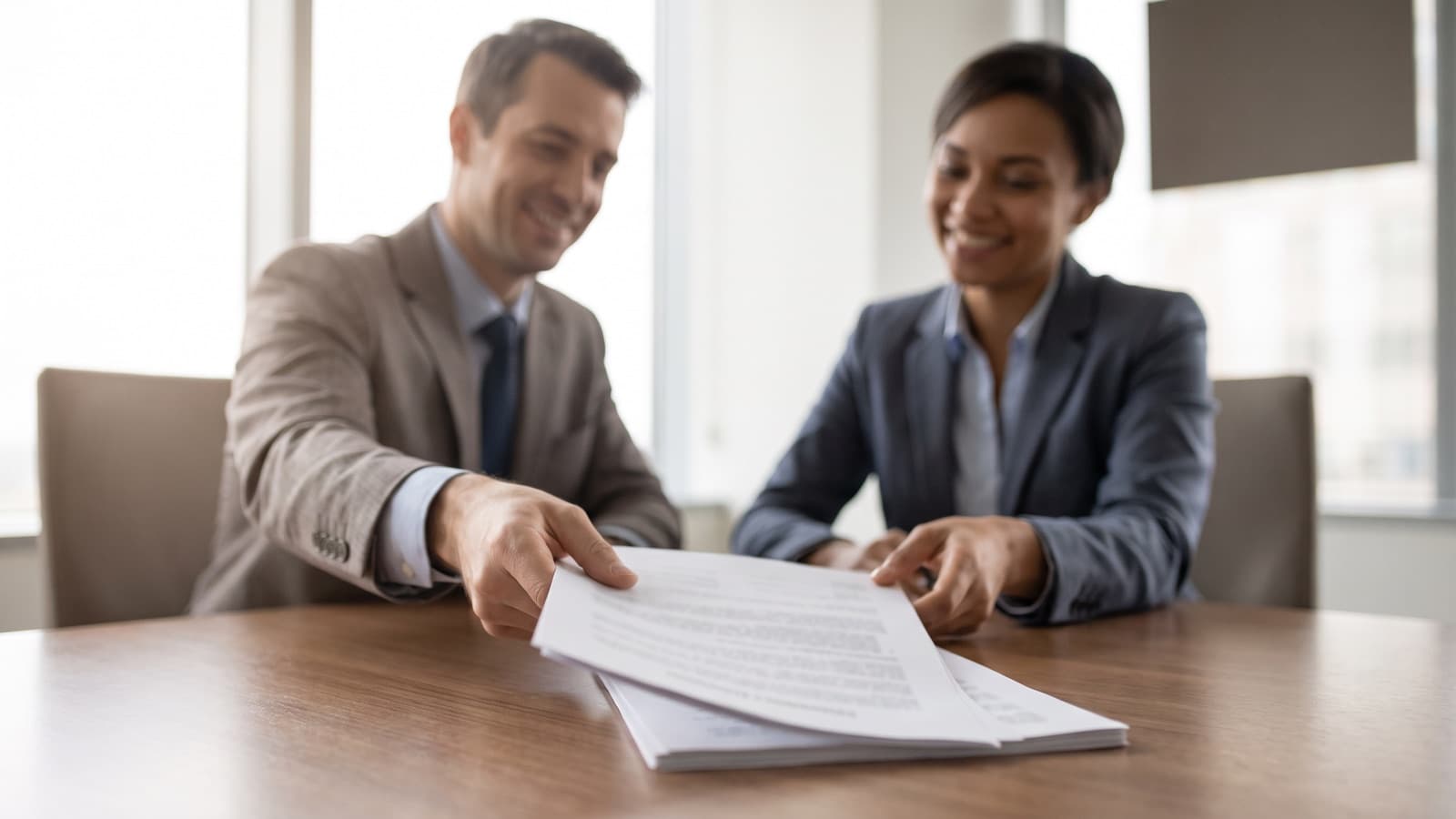 Two business owners and their lawyers reviewing a purchase agreement across a boardroom table