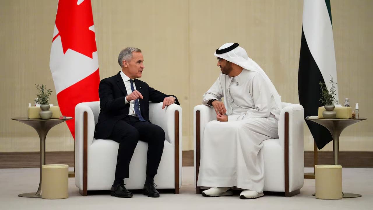 Canadian and Emirati officials seated in conversation between their two national flags