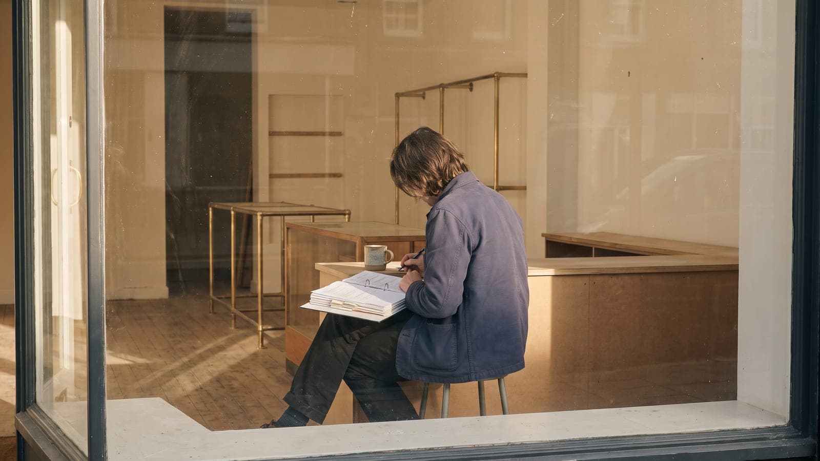 Prospective franchise buyer reviewing a binder of documents at a storefront counter